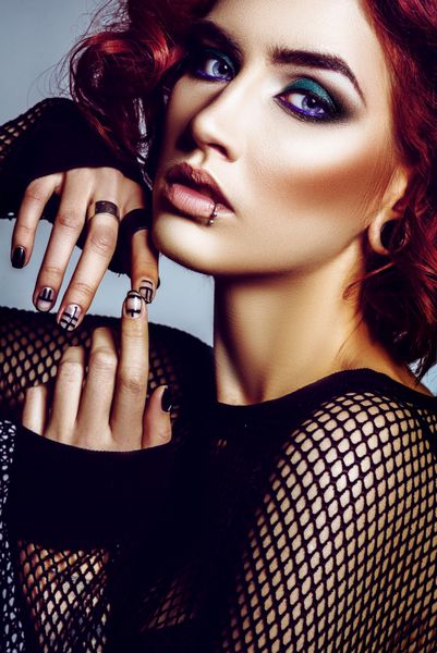مدل هیپستر دختر زیبای گوتیک با پیرسینگ با موهای قرمز هنر آرایش با لباس سیاه در استودیو