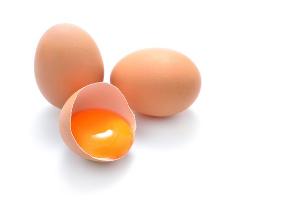 نمای نزدیک از تخم مرغ ترک خورده جدا شده در پس زمینه سفید