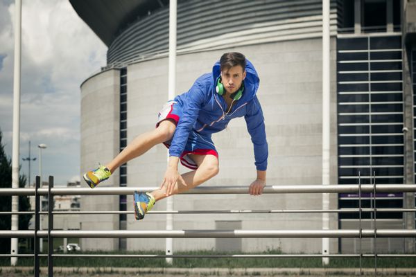 ورزشکار جوان خوش تیپ در حال پریدن از روی حصار