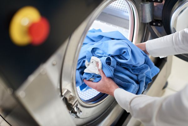 دست برای قرار دادن لباس های شسته شده در ماشین لباسشویی در خشکشویی