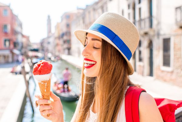 مسافر زن جوان در حال خوردن بستنی سنتی ایتالیایی به نام Gelato در مخروط وافل در ونیز