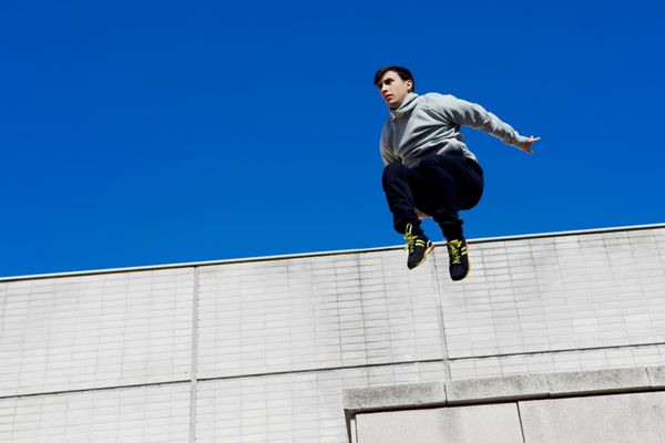 ورزشکار ردیاب جوان در حال پریدن از روی سقف ساختمان