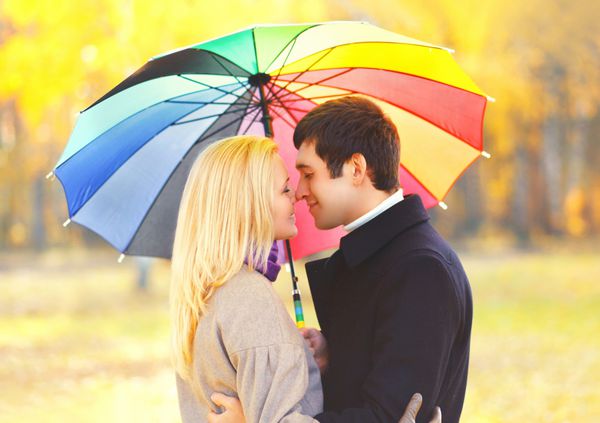 پرتره زن و شوهر عاشق بوسیدن عاشق با چتر رنگارنگ