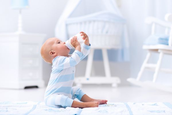 پسر بچه در حال نوشیدن شیر در مهد کودک آفتابی