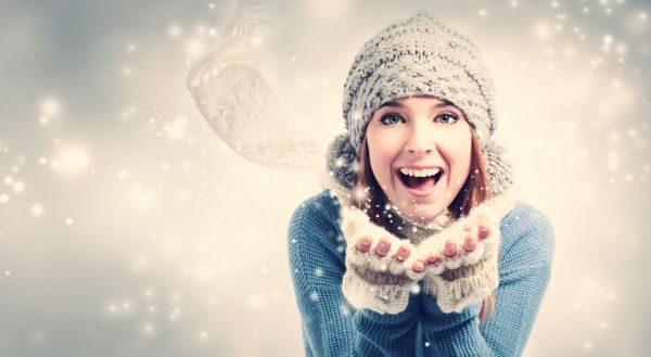 زن جوان شاد در حال دمیدن برف