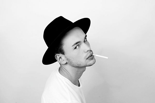 مردی با کلاه سیاه با سیگار در یک استودیو