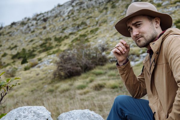 مرد جوانی با کلاه در حال شروع ماجراجویی در کوه در مونتن