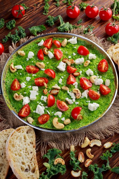 املت سبز سبزیجات با گوجه فرنگی کلم پیچ پنیر یونانی زیتون آجیل نان تست روی زمینه چوبی مفهوم غذای سالم