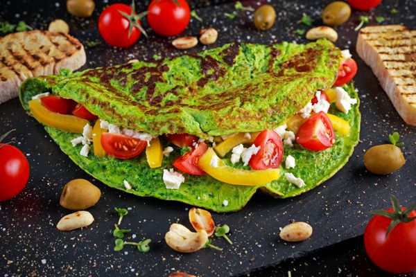املت سبز سبزیجات با گوجه فرنگی پنیر یونانی زیتون آجیل پاپریکا نان تست روی زمینه سنگی مفهوم غذای سالم
