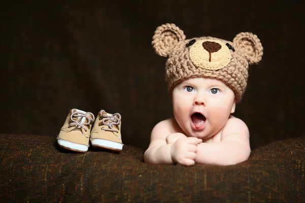 کودک ناز با کلاه خرس بافتنی و خمیازه کشیدن