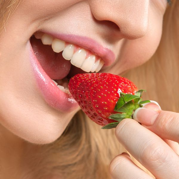 زن جوان زیبا در حال خوردن توت فرنگی