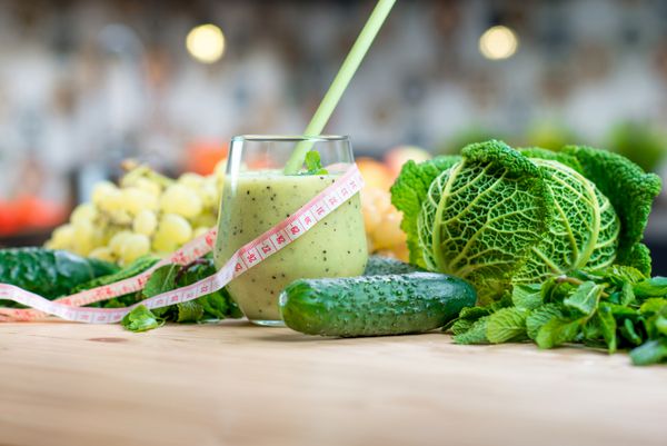 لیوان با اسموتی با سبزیجات سبز روی میز آشپزخانه رژیم گیاهخواری سالم برای کاهش وزن و سم زدایی