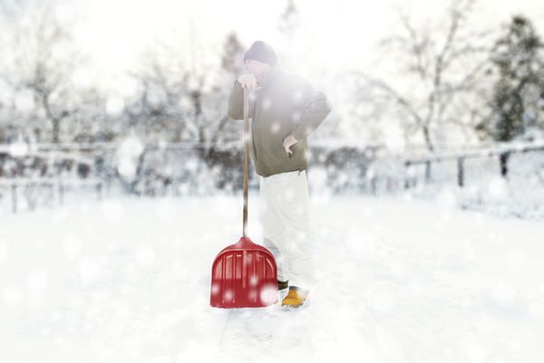 مردی که در حین بارش برف با بیل برف حیاط خلوت را پاک می کند