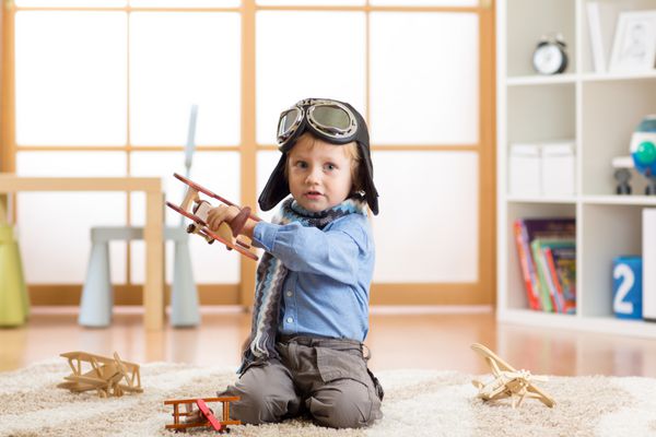 کودک ناز در آرزوی خلبان شدن پسر بچه در حال بازی با هواپیماهای اسباب بازی