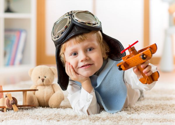 کودک نوپا شادی که با هواپیمای اسباب بازی بازی می کند و رویای خلبان شدن را دارد