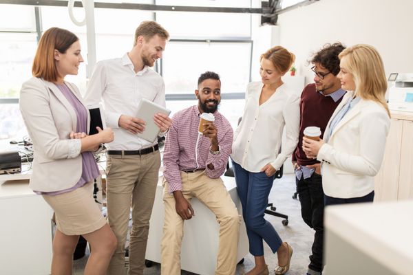 تیم تجاری خوشحال در حال نوشیدن قهوه در دفتر