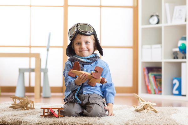 کودک نوپا خوشحالی که با هواپیمای اسباب بازی بازی می کند و رویای خلبان شدن را دارد
