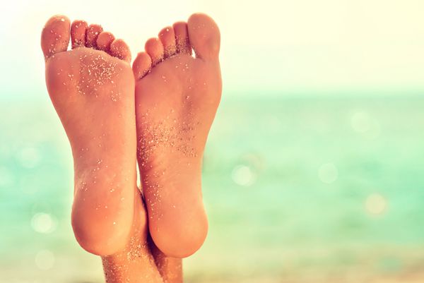 پاهای زن کامل تمیز با شن و ماسه دریا در ساحل آبگرم اسکراب و مراقبت از پا ماساژ پا