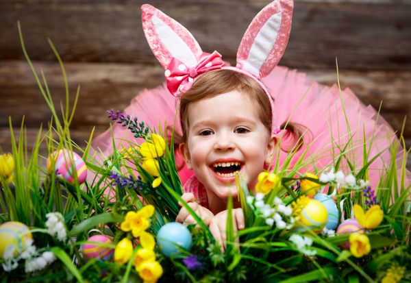 دختر بچه شاد در لباس اسم حیوان دست اموز عید پاک با تخم مرغ
