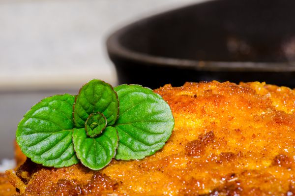 شنیسل تازه پخته شده خوشمزه با برگ نعنا برای دکور و ماهیتابه در پس زمینه