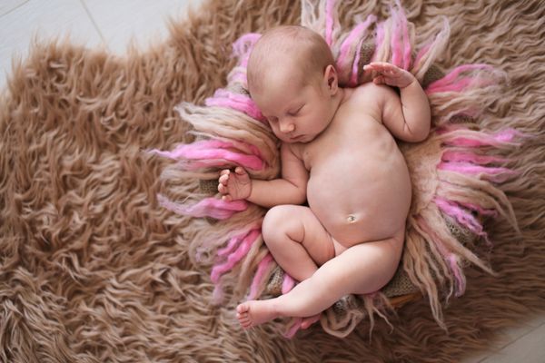 نوزاد تازه متولد شده در خواب شیرین روی پشم خز صورتی بژ