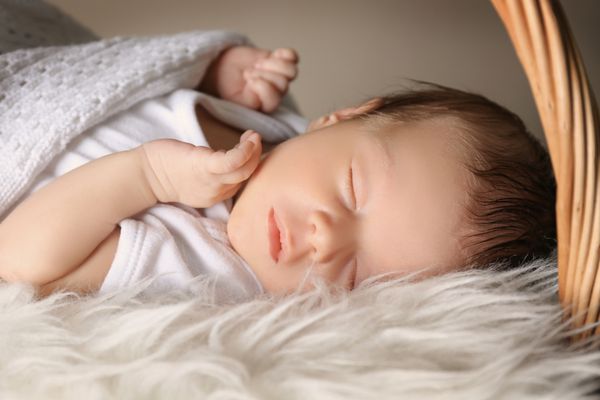 نوزاد کوچولوی ناز در سبد حصیری خوابیده نزدیک