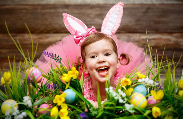 دختر بچه شاد در لباس اسم حیوان دست اموز عید پاک با تخم مرغ