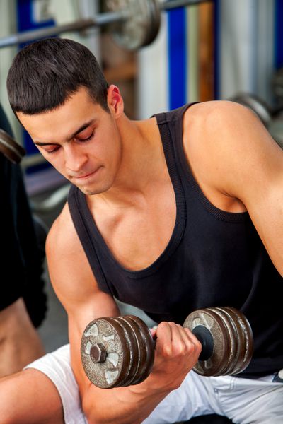 مردان در وزنه های بدنسازی با تجهیزات تناسب اندام مردی که با دمبل تمرین می کند در باشگاه دمبل های کرومی در دستان قوی مردانه