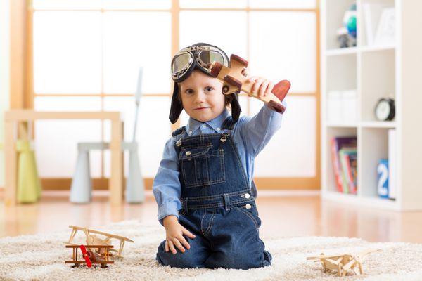 کودکی که تظاهر به هوانوردی می کند بچه بازی با هواپیماهای اسباب بازی در خانه