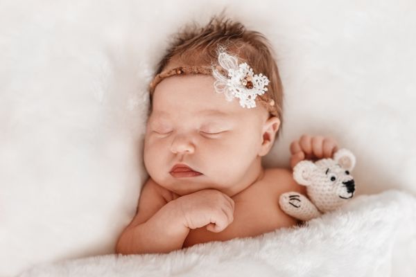 نوزاد دختر بچه خوابیده با خرس اسباب بازی بافتنی