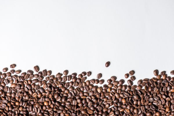 نمای بالای دانه های قهوه برشته شده در پس زمینه سفید