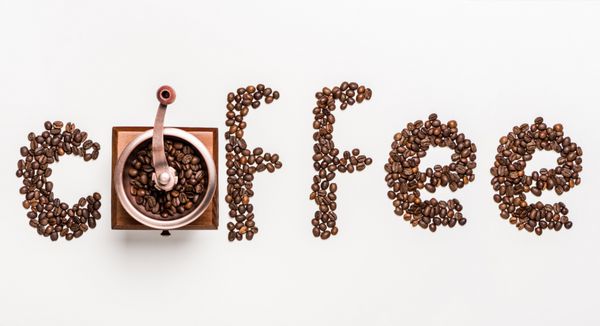 نمای بالای قهوه کلمه ساخته شده از دانه های قهوه و آسیاب قهوه