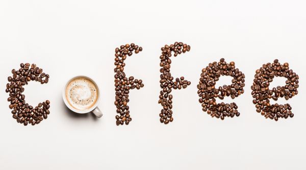 نمای بالای قهوه کلمه ساخته شده از دانه های قهوه و فنجان قهوه داغ