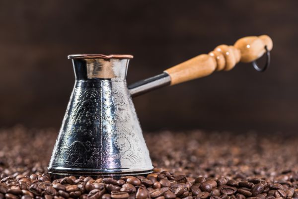 نزدیک از قوری قهوه ترکی روی دانه‌های قهوه روی مشکی