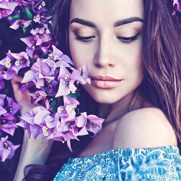 زن جوان زیبا که با گل احاطه شده است