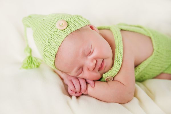 نوزاد تازه متولد شده در کلاه سبز بافتنی خوابیده است