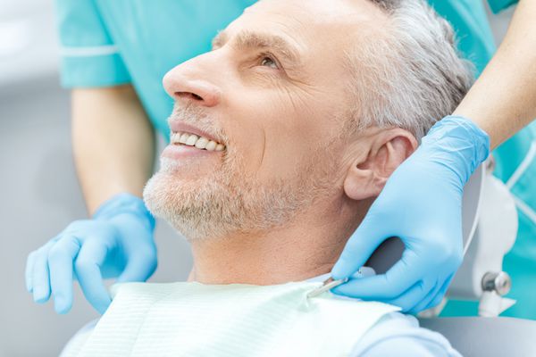 عکس برش خورده بیمار بالغ و دندانپزشک خندان در دستکش های پزشکی