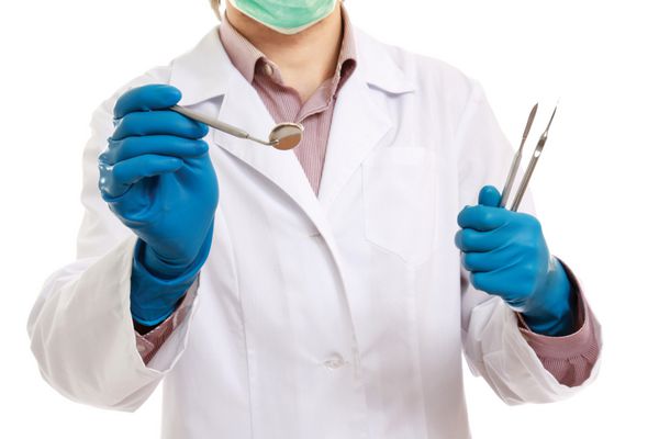 یک دندانپزشک مرد با ابزاری در دستانش