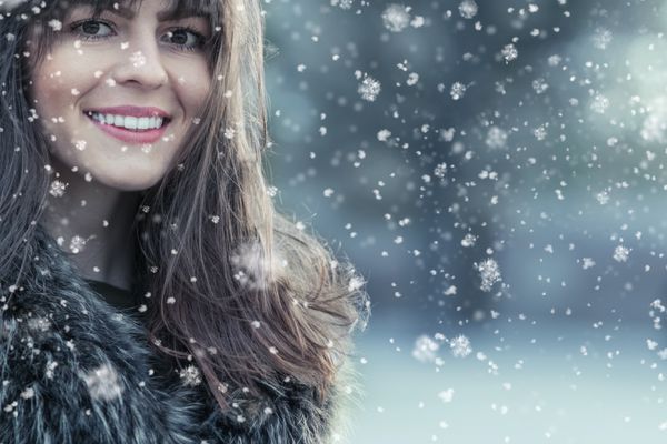 پرتره یک زن جوان لبخند در یک روز برفی زمستانی