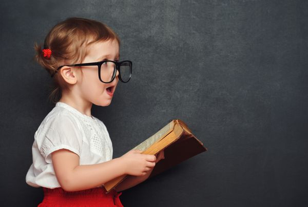 دختر مدرسه ای شاد خنده دار با کتاب از تخته سیاه