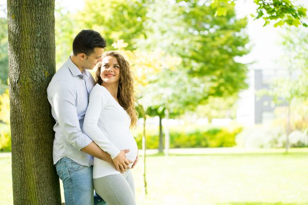 زوج باردار شاد و جوان در تابستان در پارک