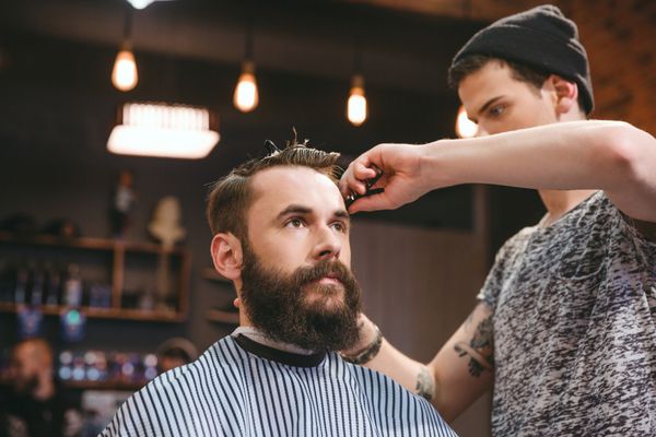 کوتاه کردن موهای مرد جوان با ریش توسط آرایشگر ماهر