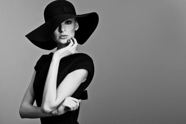 پرتره مد بالا از زن ظریف با کلاه و لباس سیاه و سفید شات استودیویی