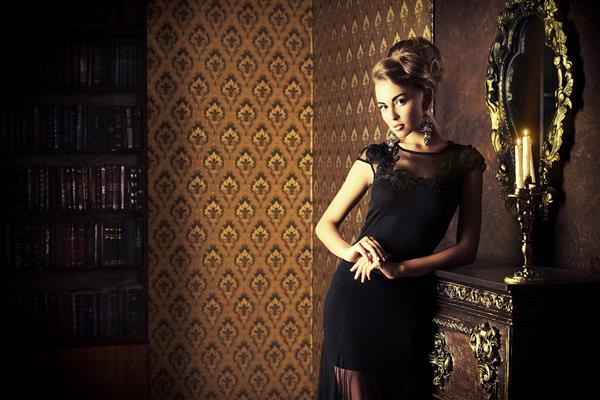 زن جوان زیبا با لباس شب سیاه که در فضای داخلی قدیمی ژست گرفته است مد شات