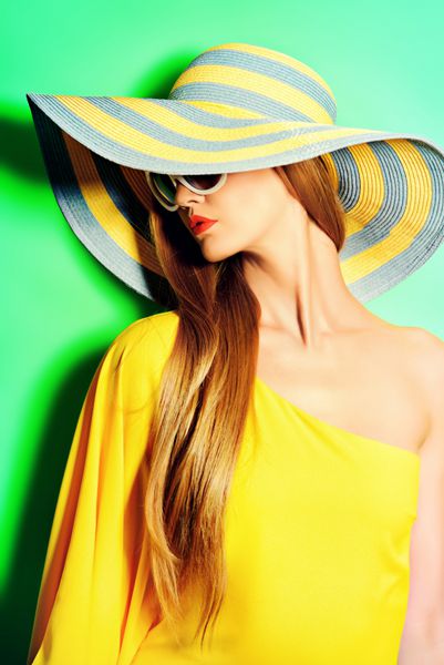 پرتره یک خانم شیک پوش خیره کننده با لباس زرد روشن که روی پس زمینه سبز ژست گرفته است زیبایی مفهوم مد رنگ های تابستان