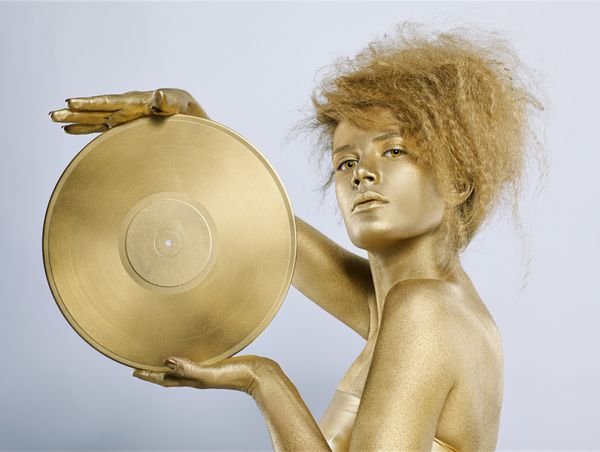 پرتره دختری با بادی‌آرت طلایی که دیسک وینیل طلایی را در دست روی خاکستری دارد