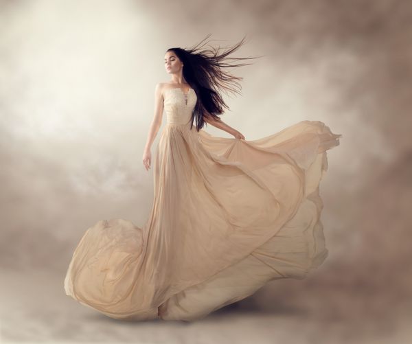 مدل مد در لباس شیفون شیفون بژ لوکس زن با لباس شب بلند پرنده با لباس مجلسی مدل فانتزی خیره کننده پارچه ابریشمی که روی باد تکان می‌خورد پارچه ساتن جاری امواج یک لباس
