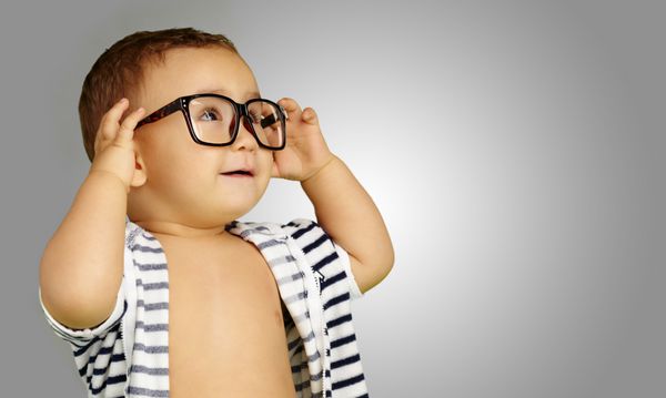 پرتره نوزاد پسری که عینک می‌زند در پس زمینه خاکستری