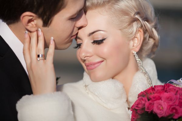 عروس و داماد در حال بوسیدن زوج عاشق با دسته گل های رز در روز عروس زمستانی از لحظات شادی و لذت لذت ببرید زن خانواده تازه ازدواج کرده بازیگوش و مرد عاشق عروس خوشگل