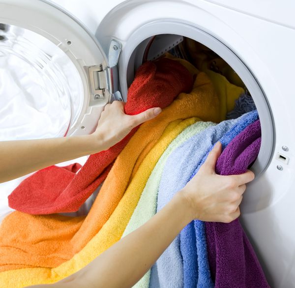 زن در حال گرفتن لباس های رنگی از ماشین لباسشویی